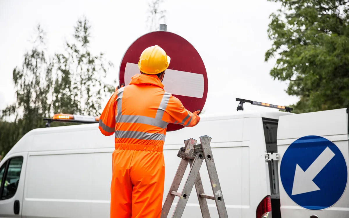 A worker mounting a sign beside a work van