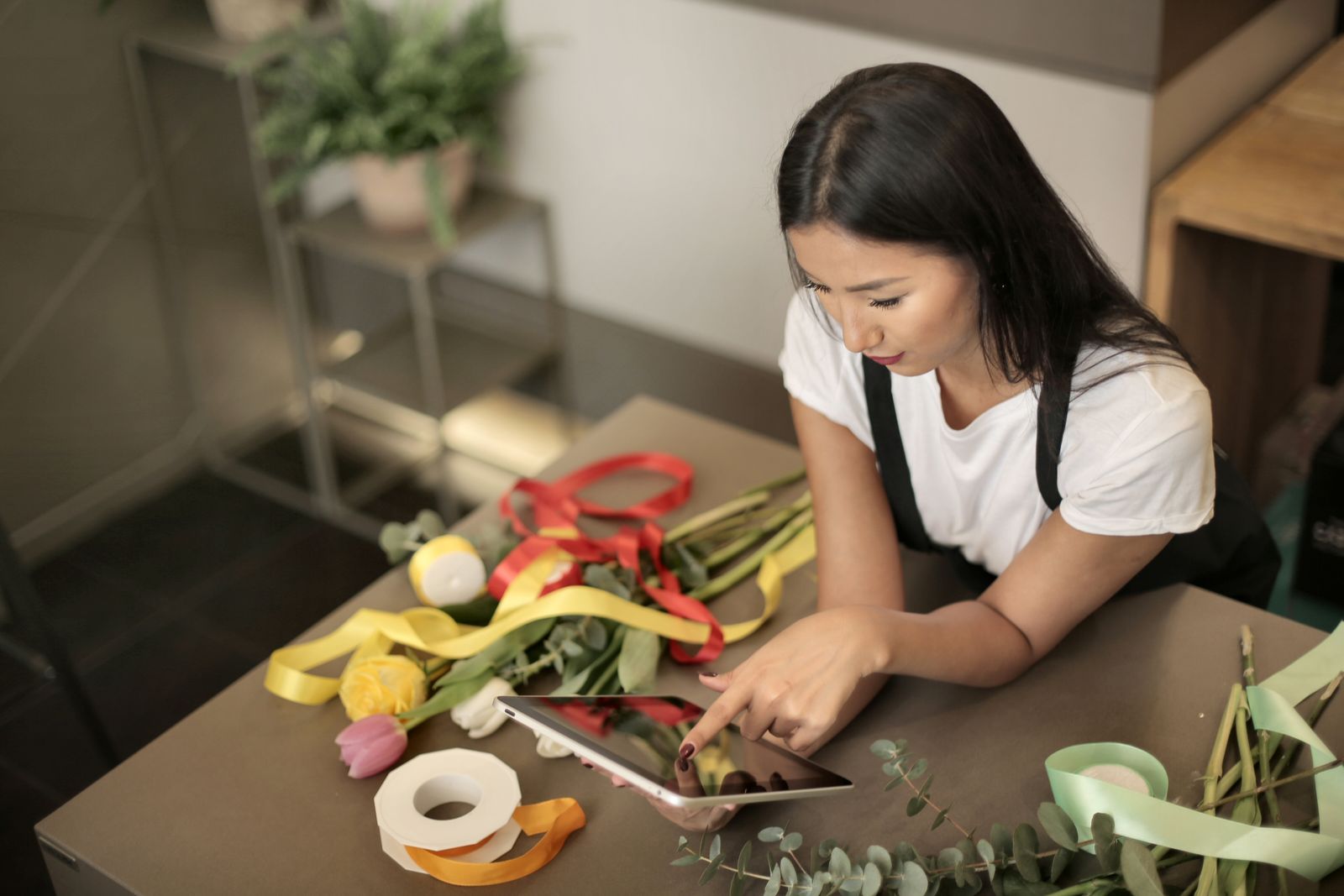 A florist checks her shop's orders on a tablet at the counter